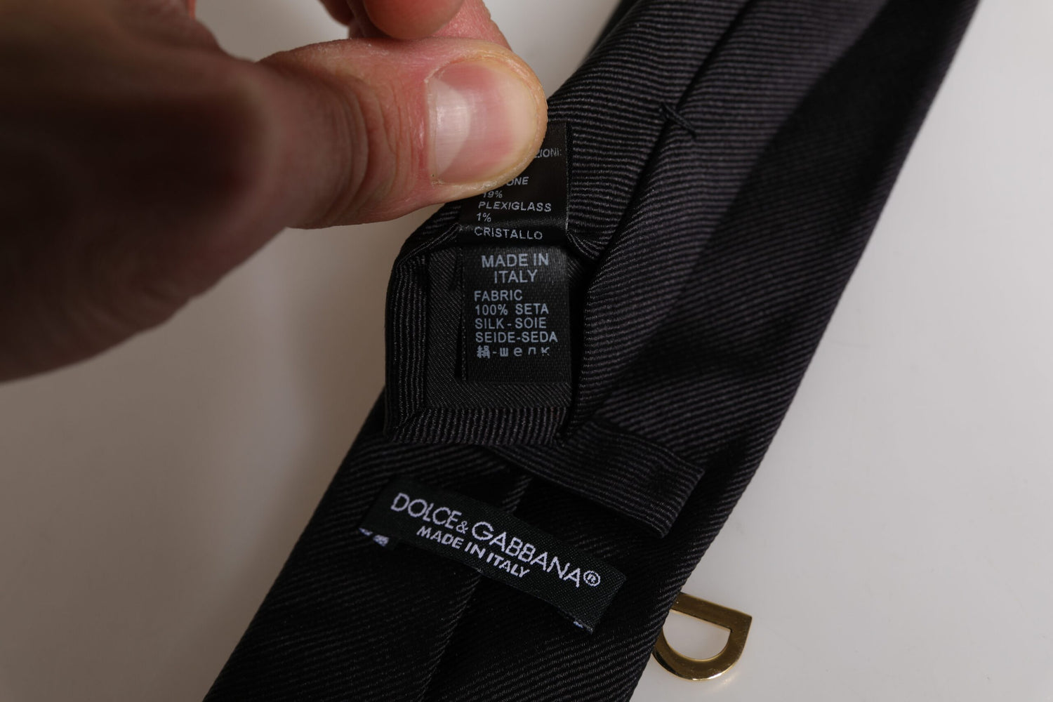 Close-up of a Dolce & Gabbana label on a black garment with a hand holding it.