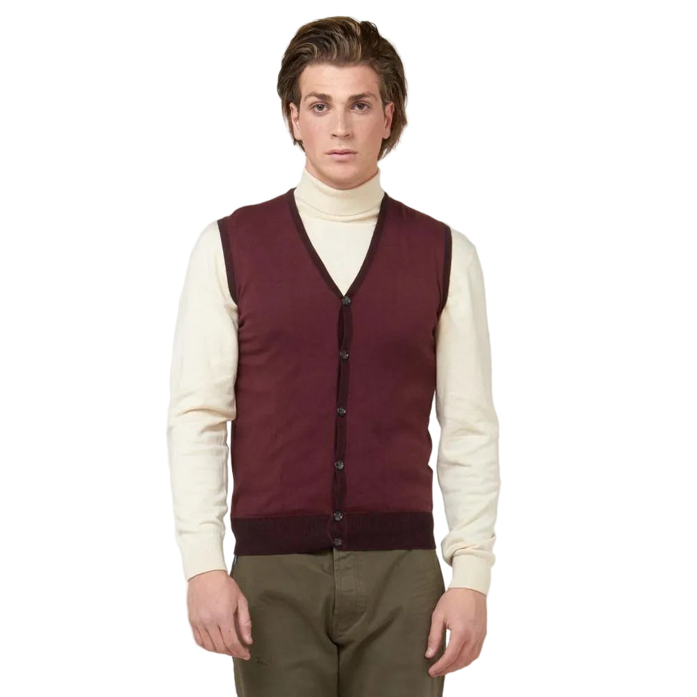 Man wearing a burgundy vest over a cream turtleneck sweater on a light gray background