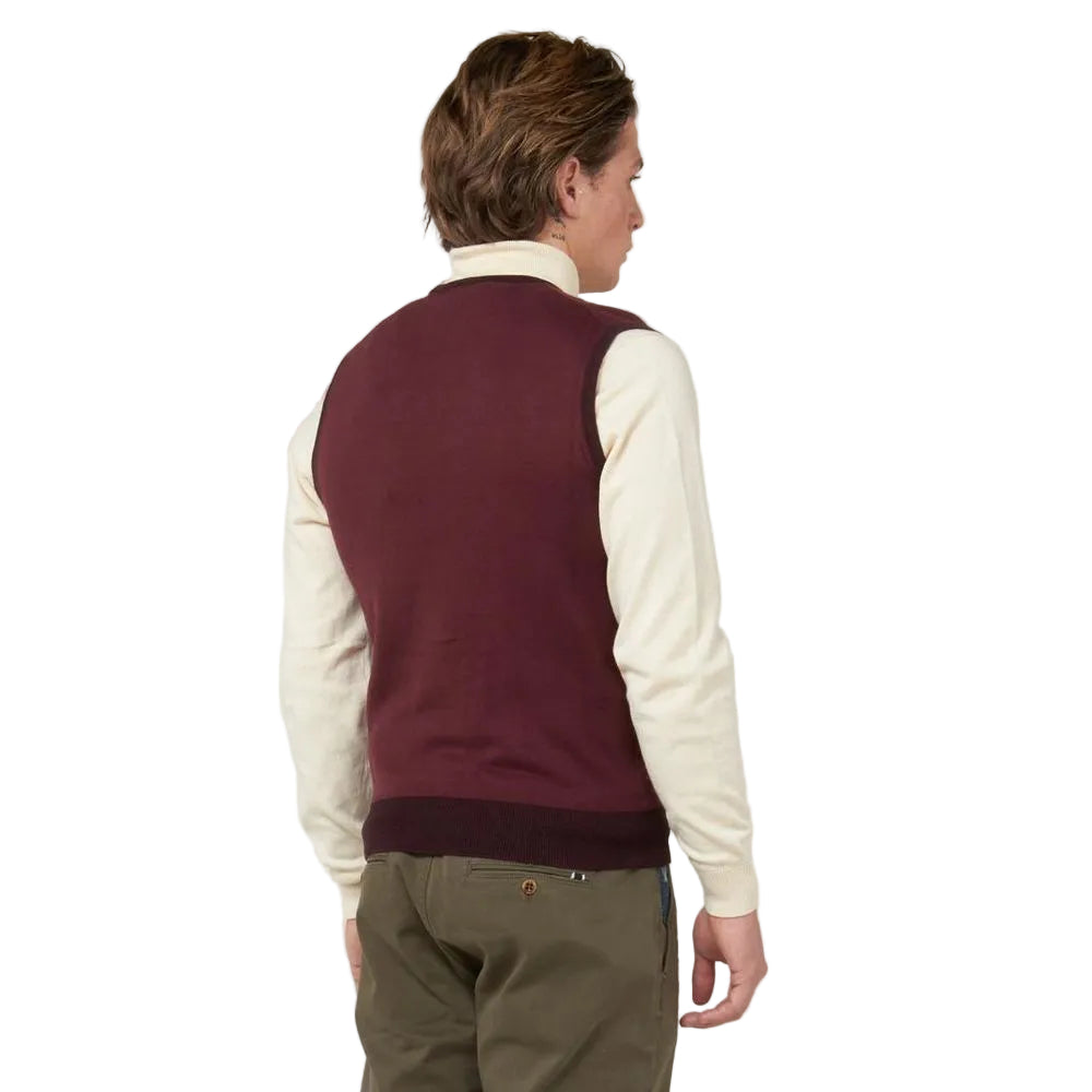 Person wearing a maroon vest over a white shirt on a plain background