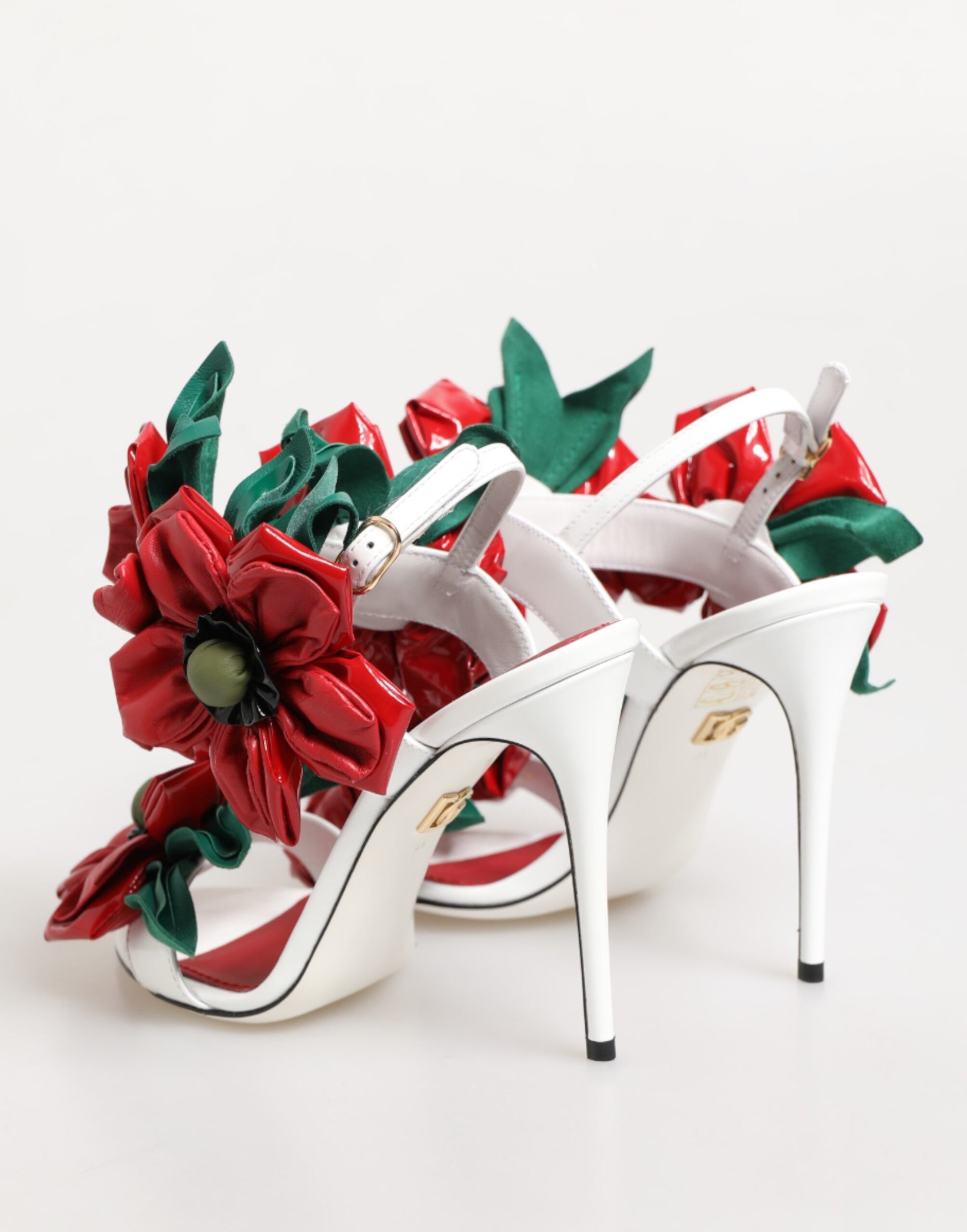 White high-heeled shoes with red floral decorations on a white background