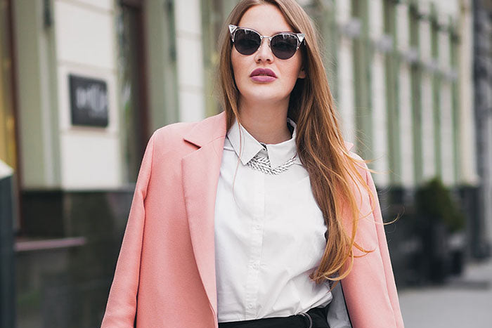 Woman wearing a pink coat and sunglasses on a city street