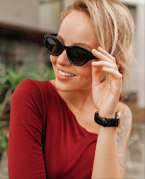Woman wearing sunglasses and a red top, with a blurred background