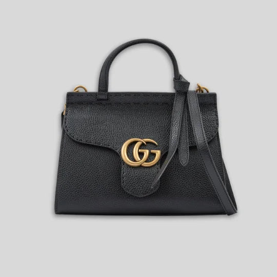 Black handbag with gold logo on a light gray background