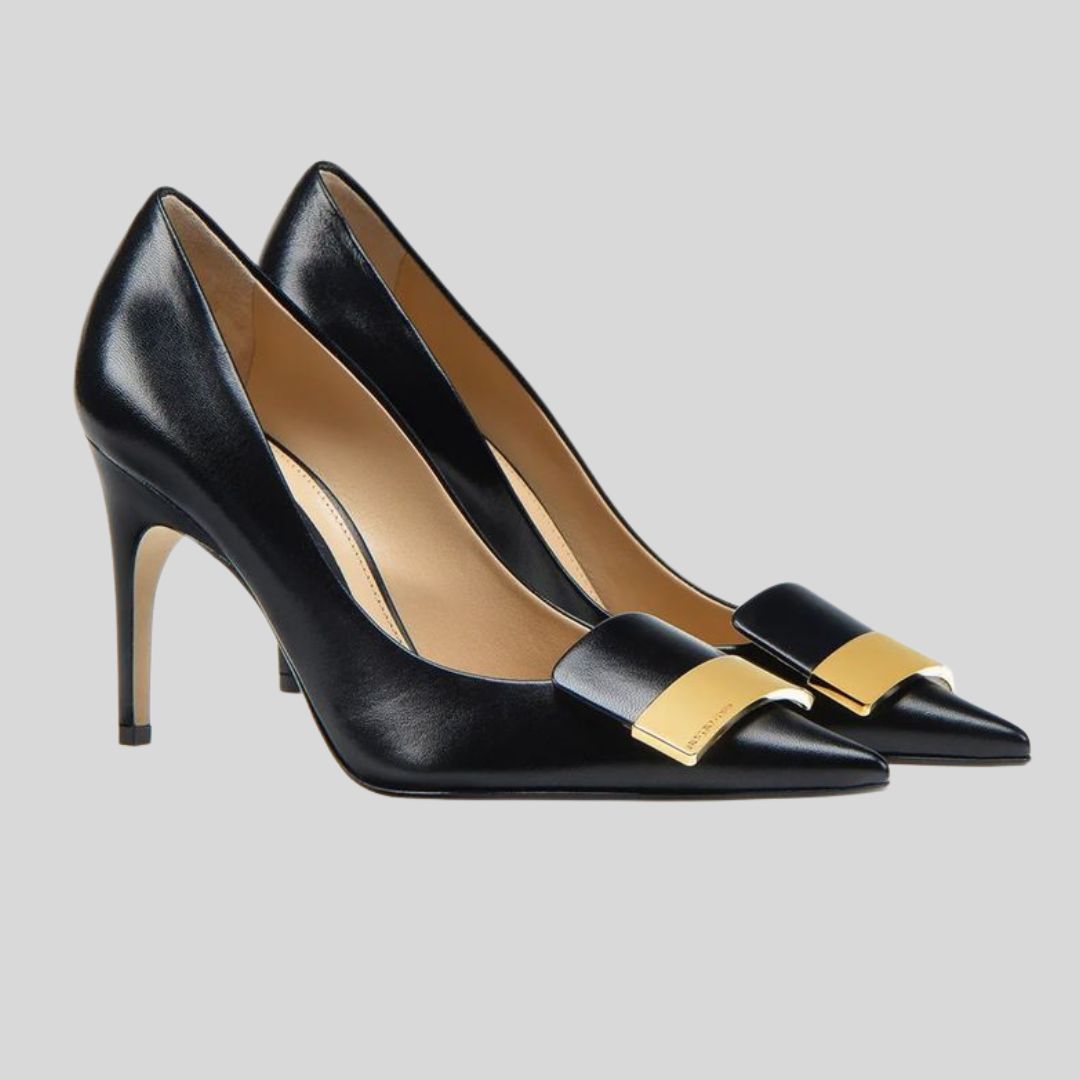 Black high-heeled shoes with gold accents on a light gray background